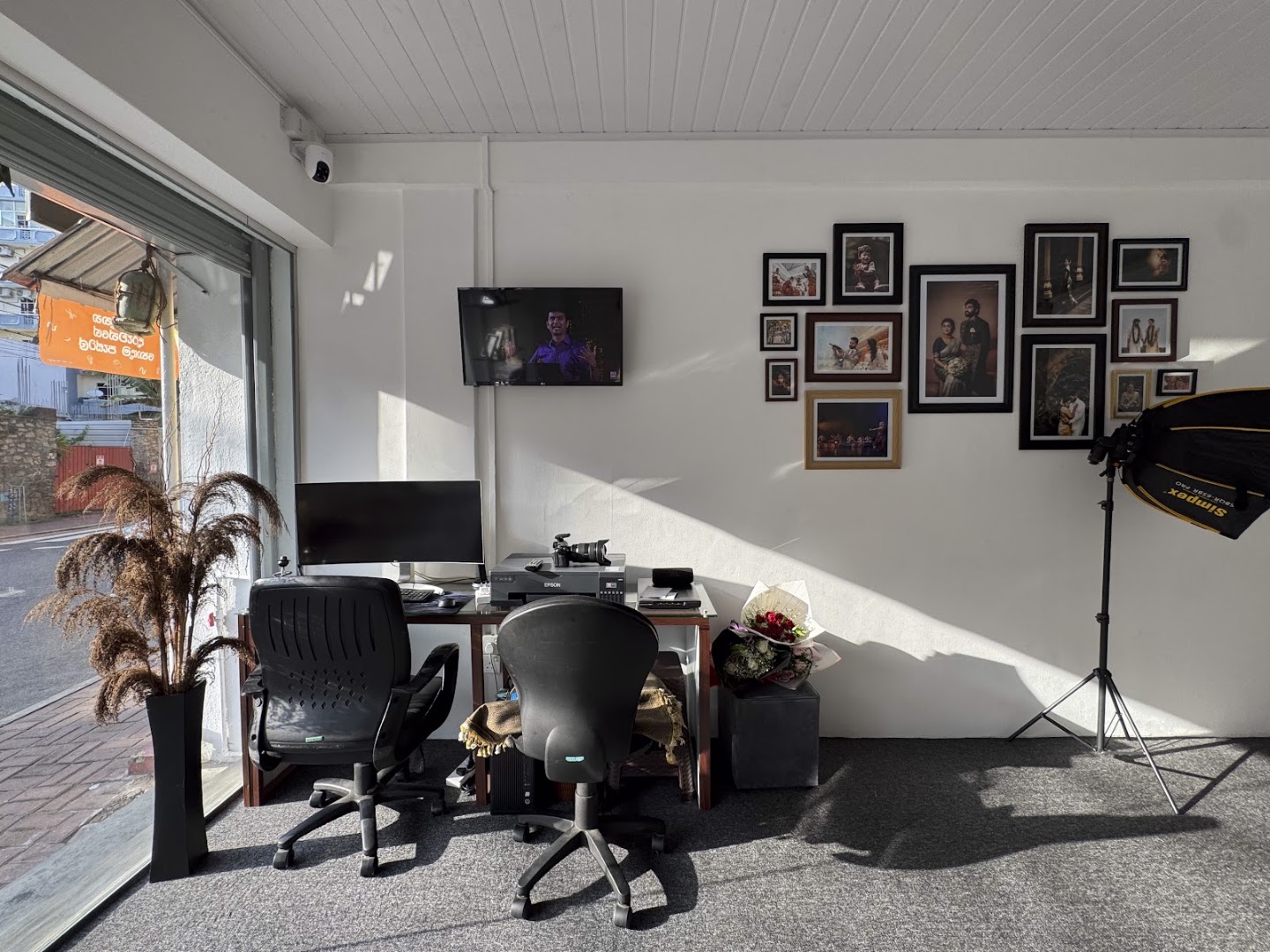 The studio floor, lighting set up and framed work covering the walls