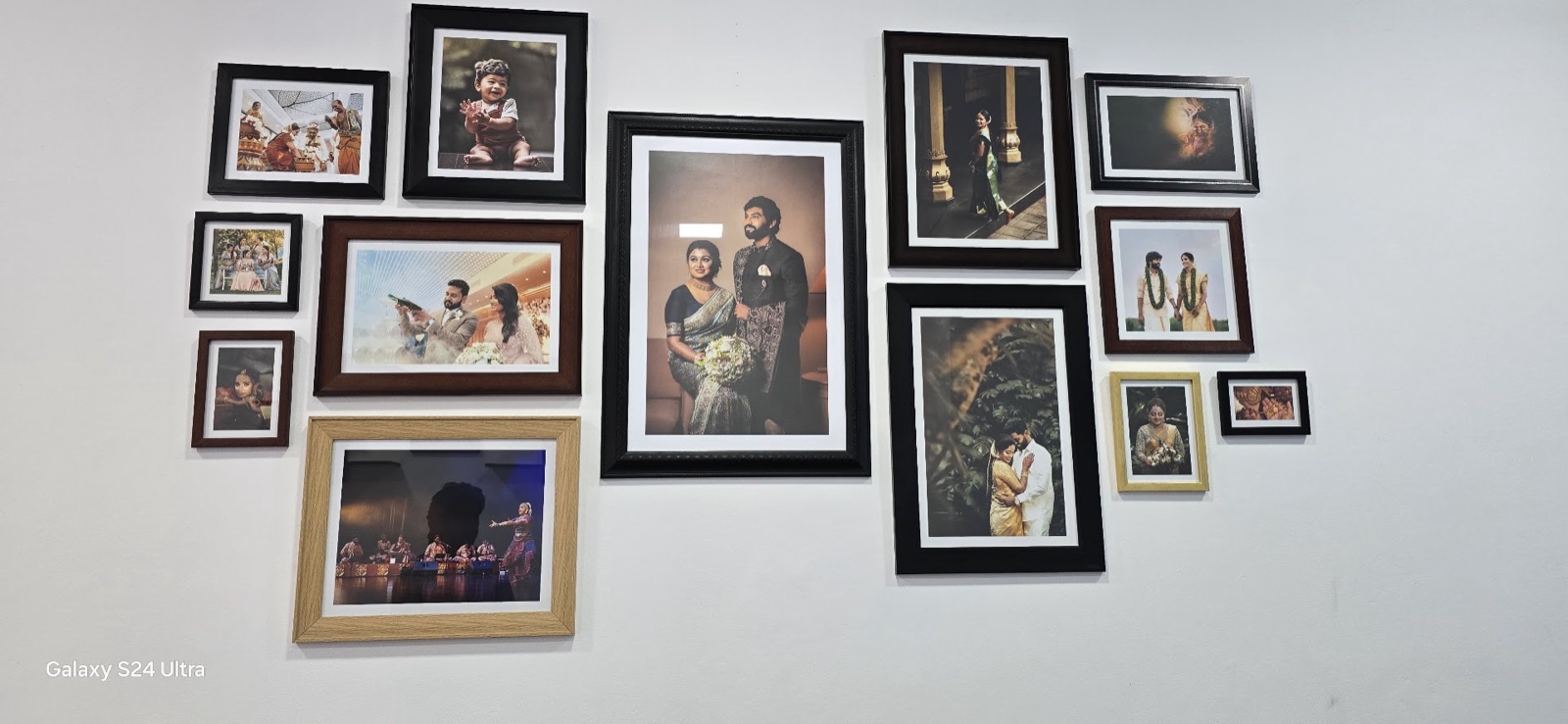 A wall of framed family and wedding portraits printed at the studio